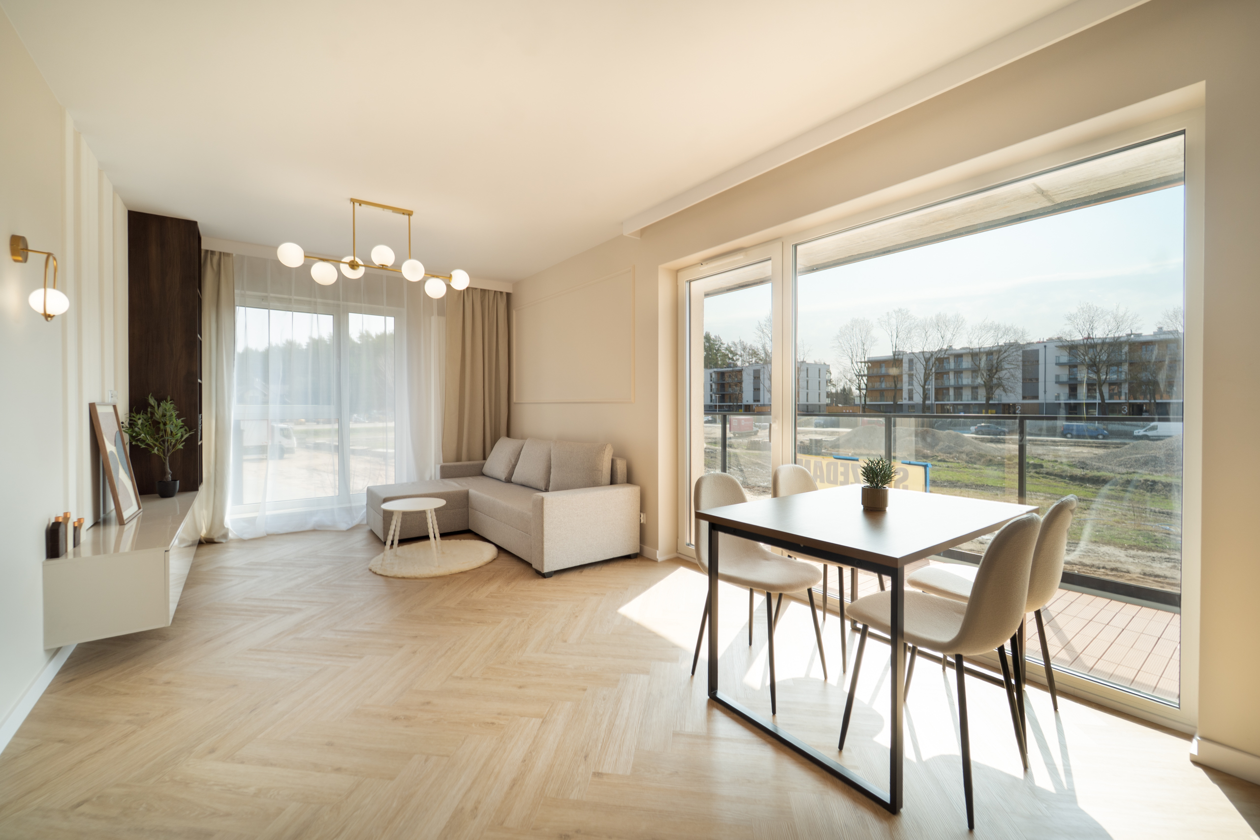 Nowoczesny salon z jadalnią, dużymi oknami i jasnym wystrojem