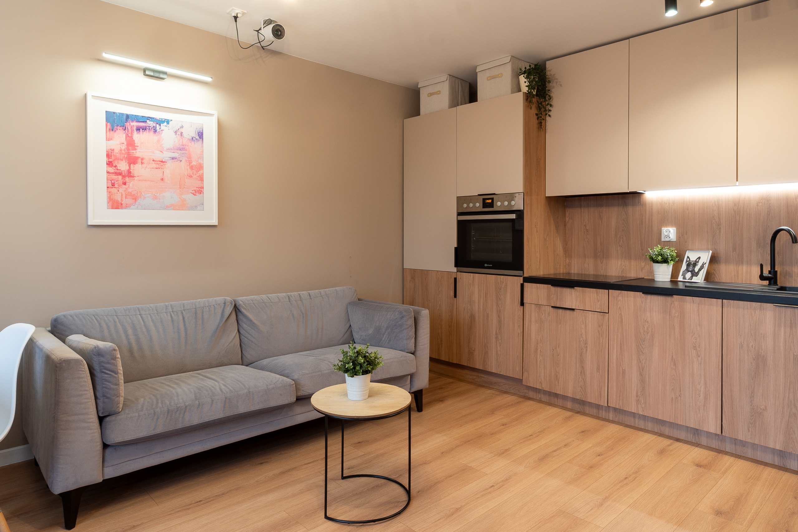 Nowoczesny salon z aneksem kuchennym, szary sofa i drewniane elementy