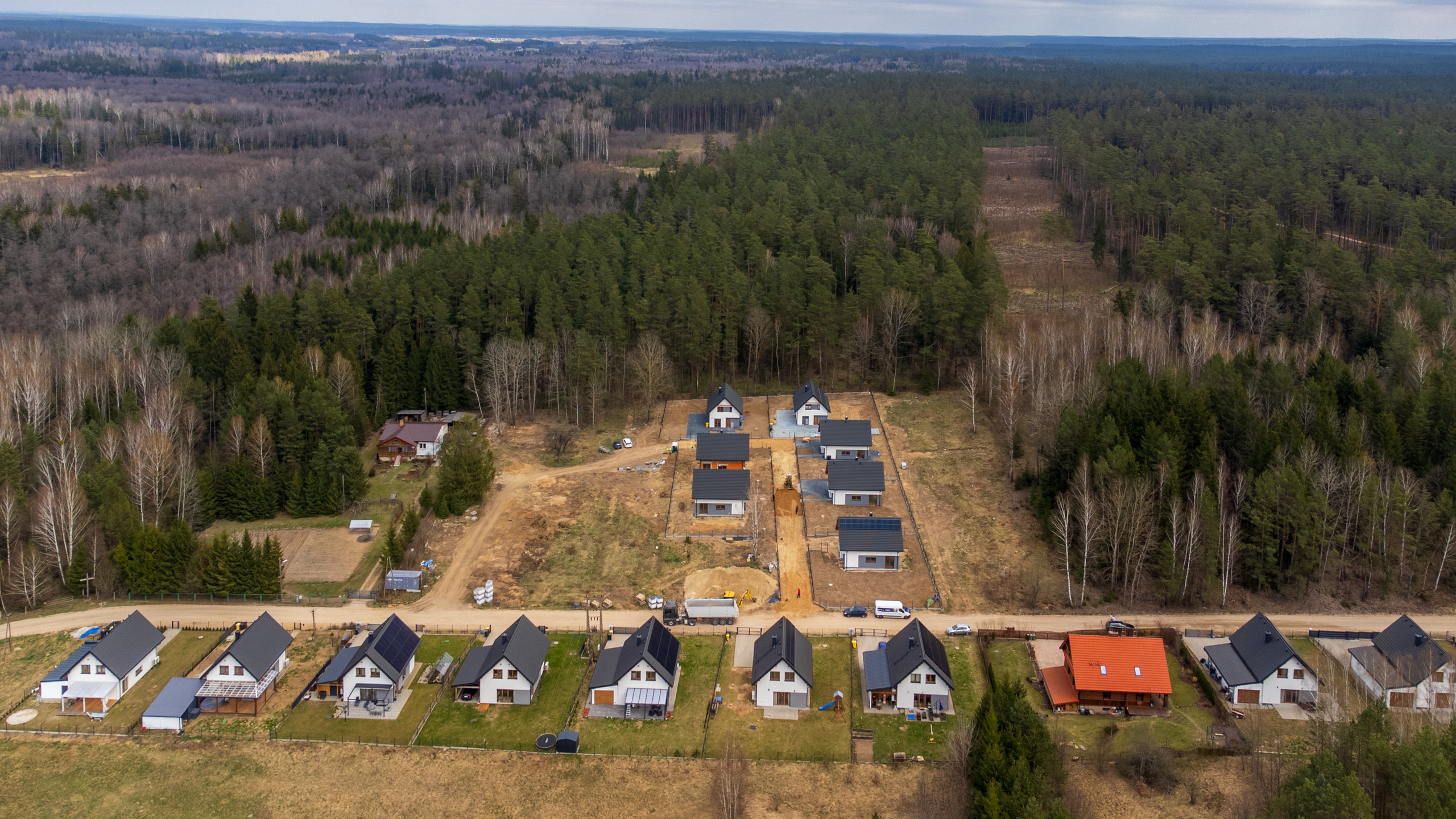 Widok z drona na osiedle domów jednorodzinnych otoczone lasem