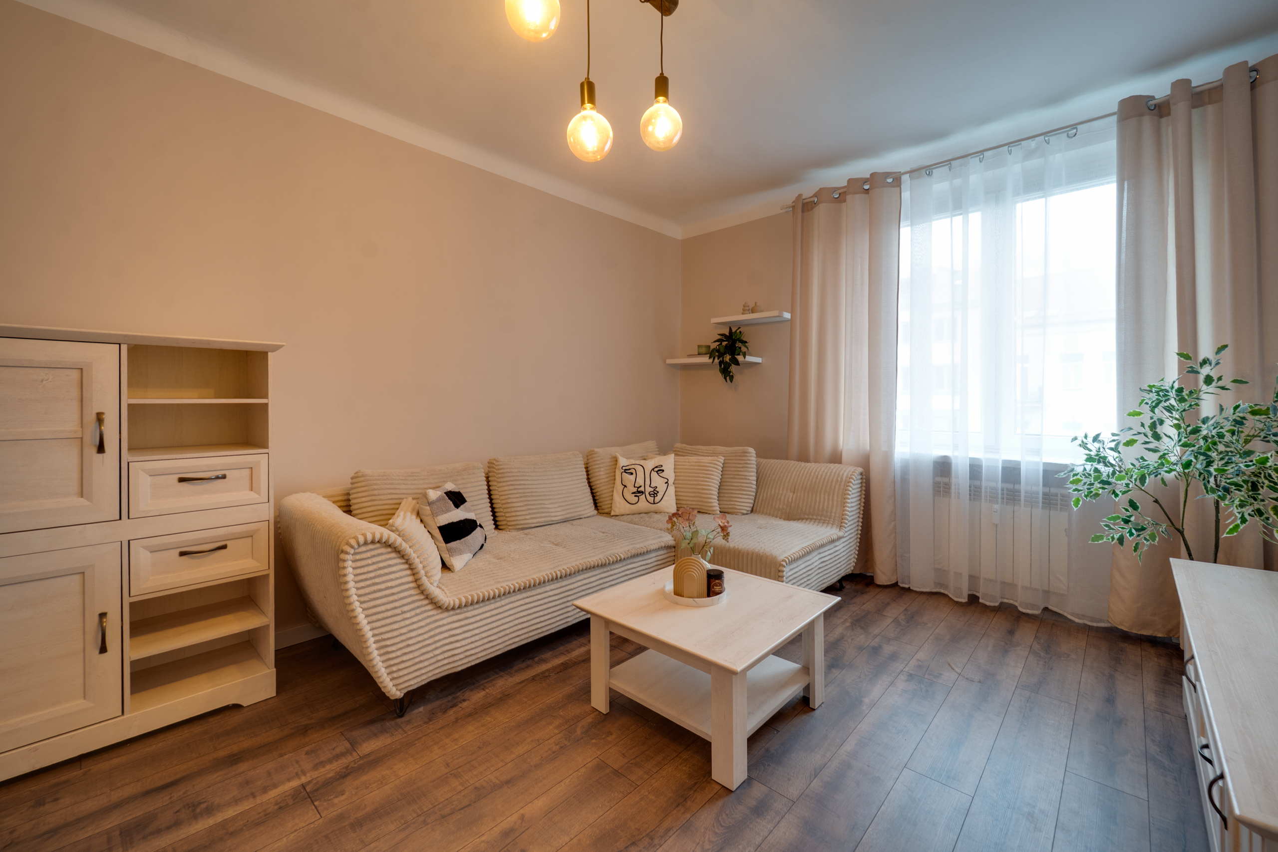 Stylowy salon z kanapą, drewnianą podłogą i dużym oknem