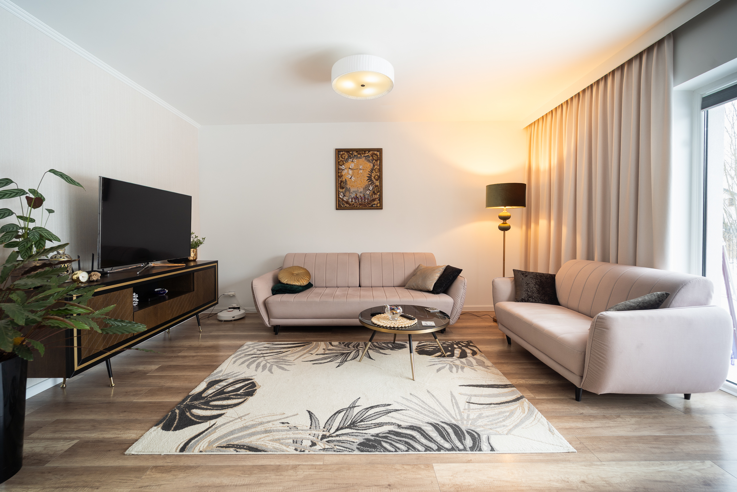 Nowoczesny salon z różowymi sofami, telewizorem i lampą