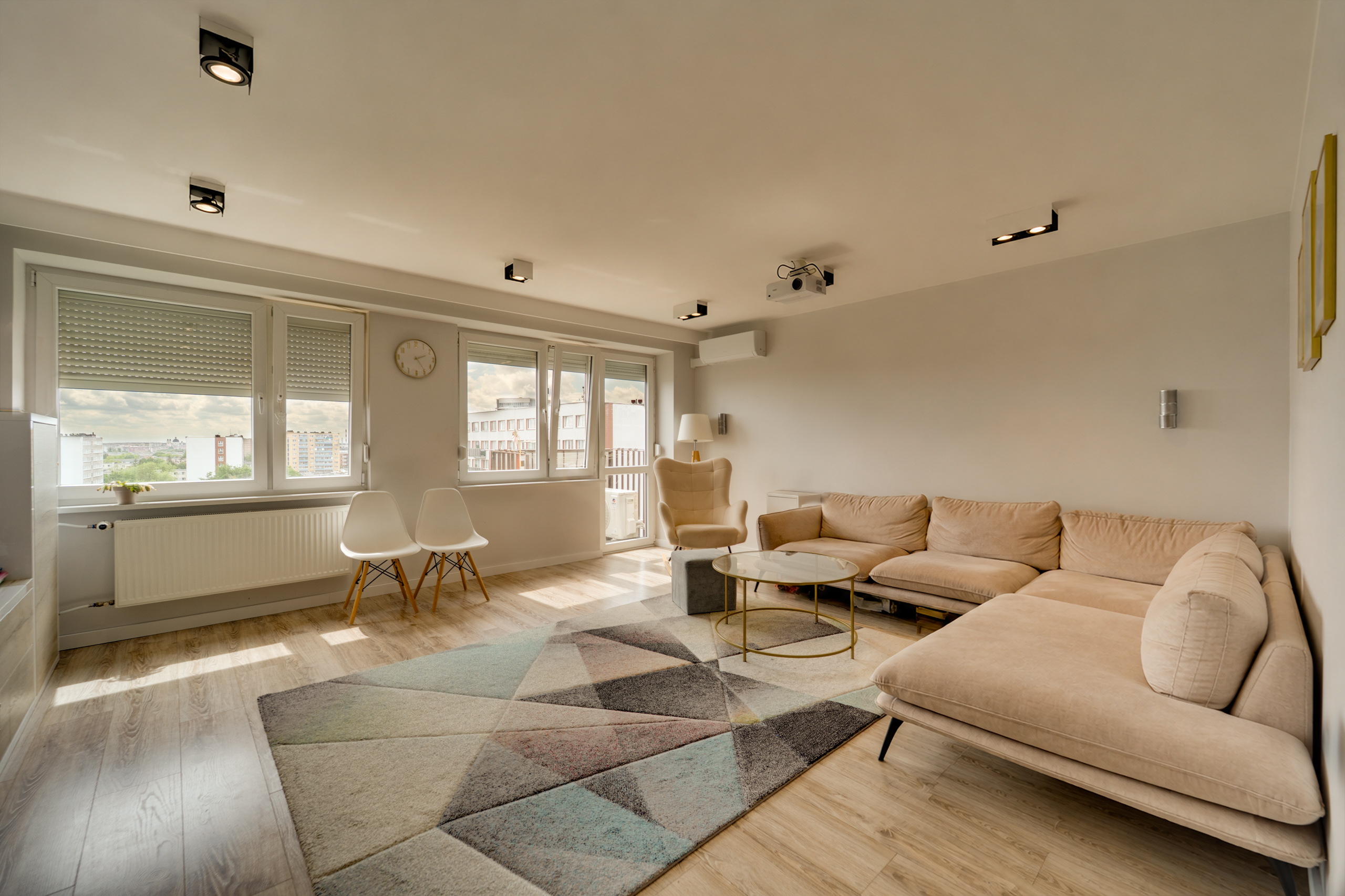 Nowoczesny salon z jasnym wystrojem, dużymi oknami i wygodną sofą